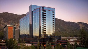A modern hotel with a glass facade, multiple floors, and a prominent Harrah's sign.