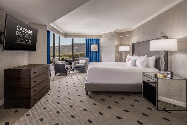 A hotel room with a bed, a dresser, a desk with a lamp, a chair, and a television displaying 'CAESARS REPUBLIC LAKE TAHOE'. - Caesars Republic Lake Tahoe Hotel & Casino - A Caesars Rewards Destination (Stateline)