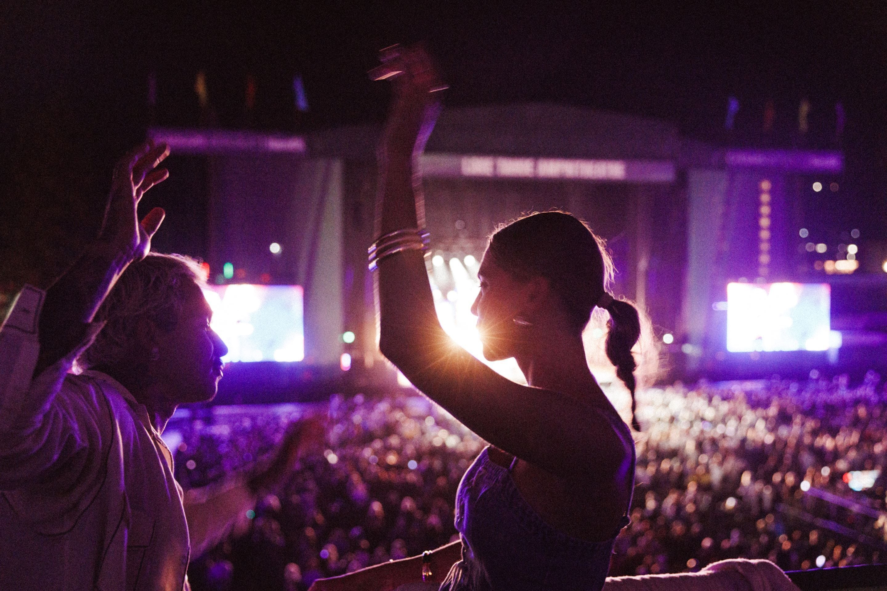 Un concert avec un public nombreux et un jeu de lumière élaboré sur scène.