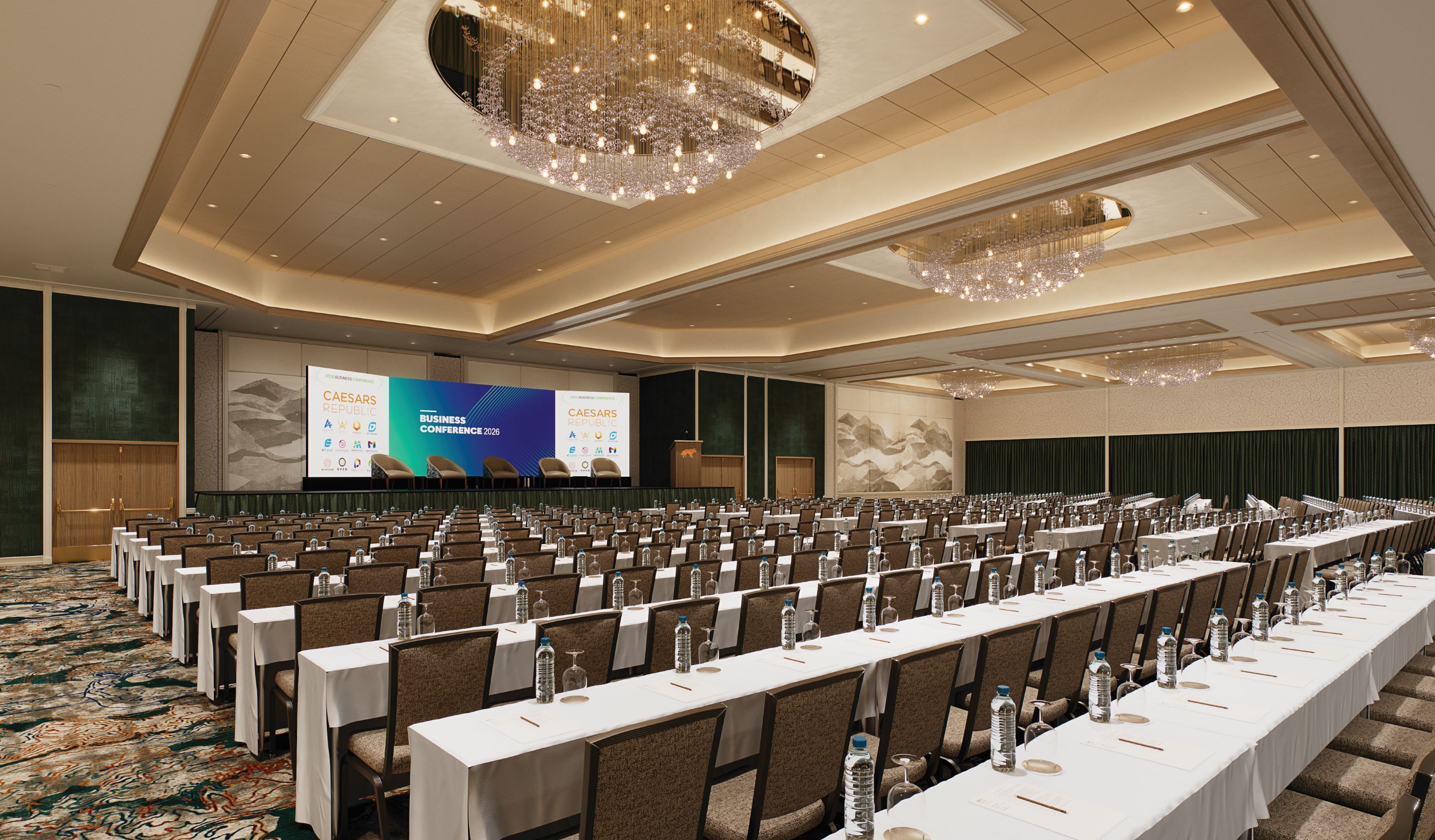A conference room with rows of tables and chairs, a large screen displaying a presentation, and a chandelier.