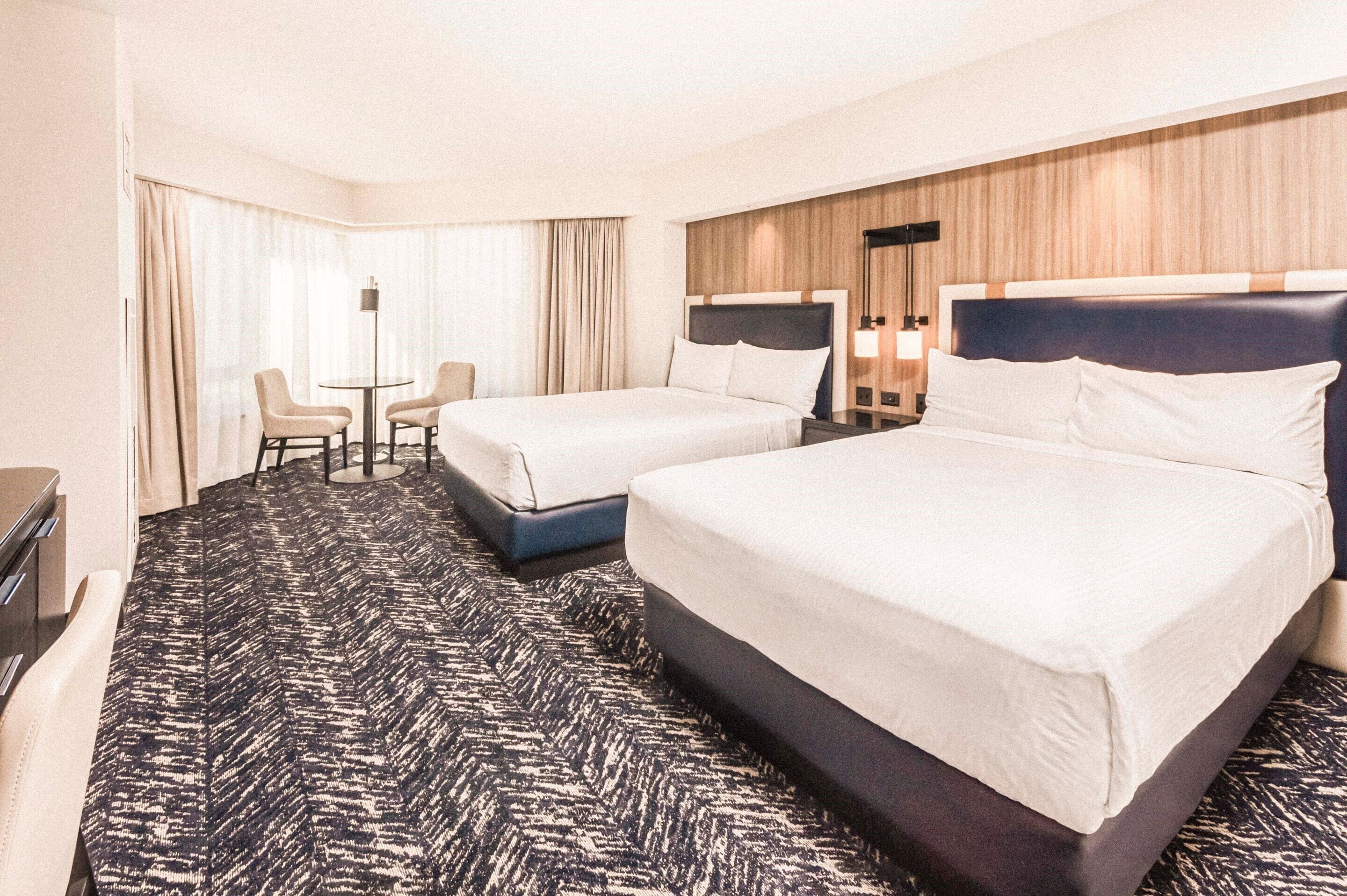 Ein Hotelzimmer mit zwei Betten, einem Schreibtisch und einem Stuhl.