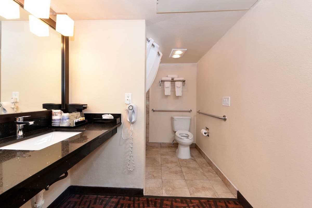 A hotel bathroom with a sink, mirror, telephone, toilet, and towel rack.