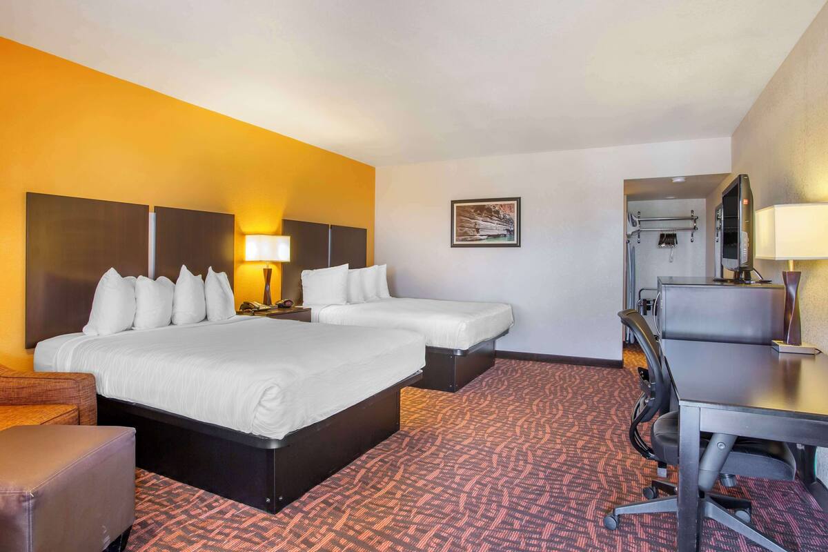 A hotel room with a large bed, two bedside tables, a desk, and a chair.