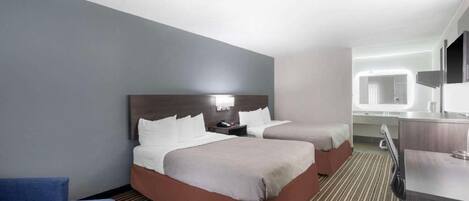 A hotel room with two beds, a desk, a chair, and a large mirror.