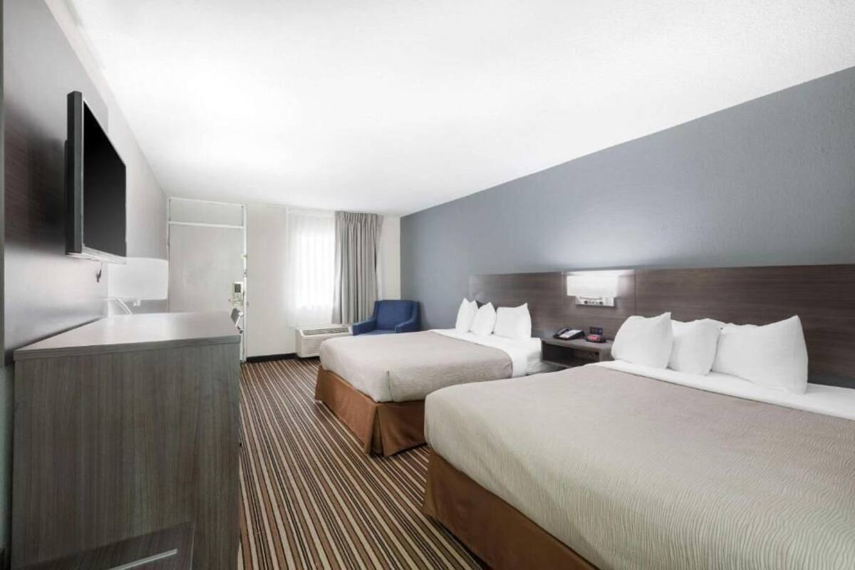 A hotel room with two beds, a TV, a desk, and a chair.