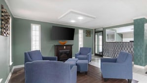 Een woonkamer met een open haard, een flatscreen-tv en een keukenruimte zichtbaar door een geopende deur.