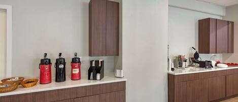 A modern kitchen with wooden cabinets, a white countertop, and various appliances including a coffee machine and a kettle.