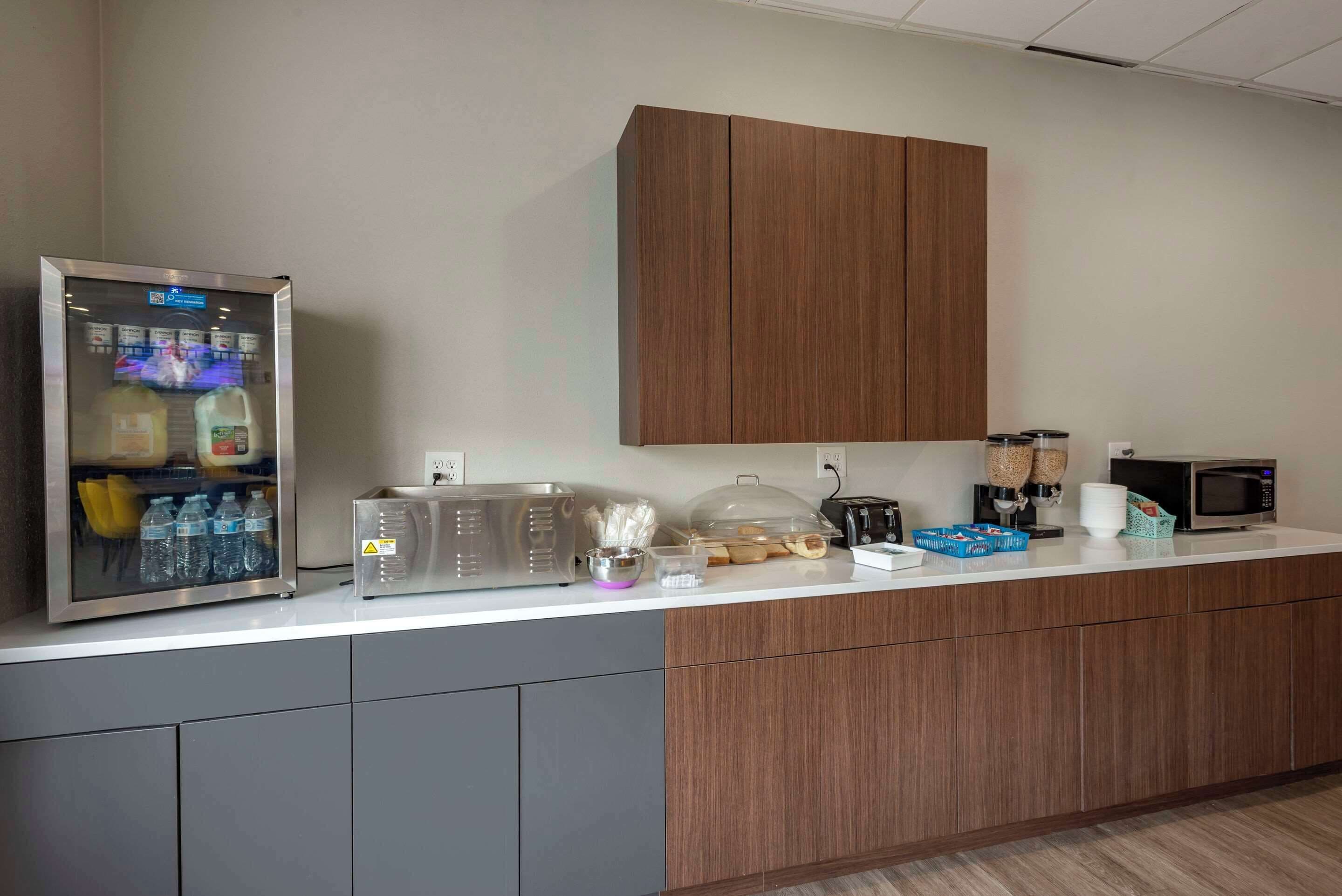 A kitchenette with a refrigerator, microwave, and coffee maker.