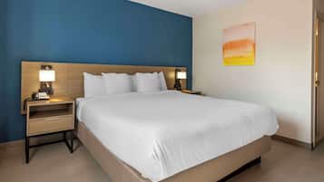A hotel room with a large bed, two bedside tables with lamps, a nightstand with a phone, and a painting on the wall.