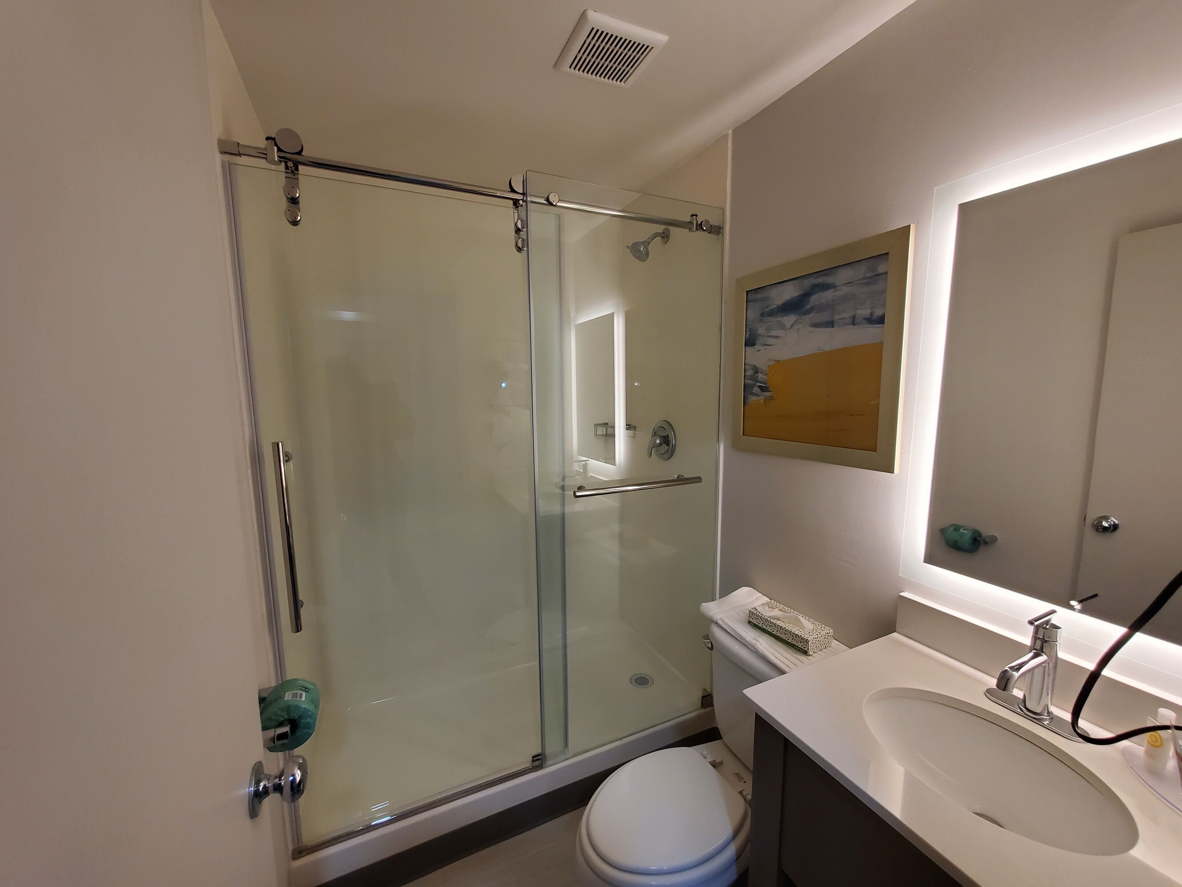 A modern bathroom with a glass-enclosed shower, a white sink, and a toilet.