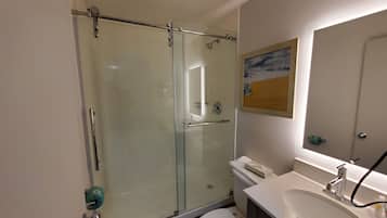 A modern bathroom with a glass-enclosed shower, a white sink, and a toilet.