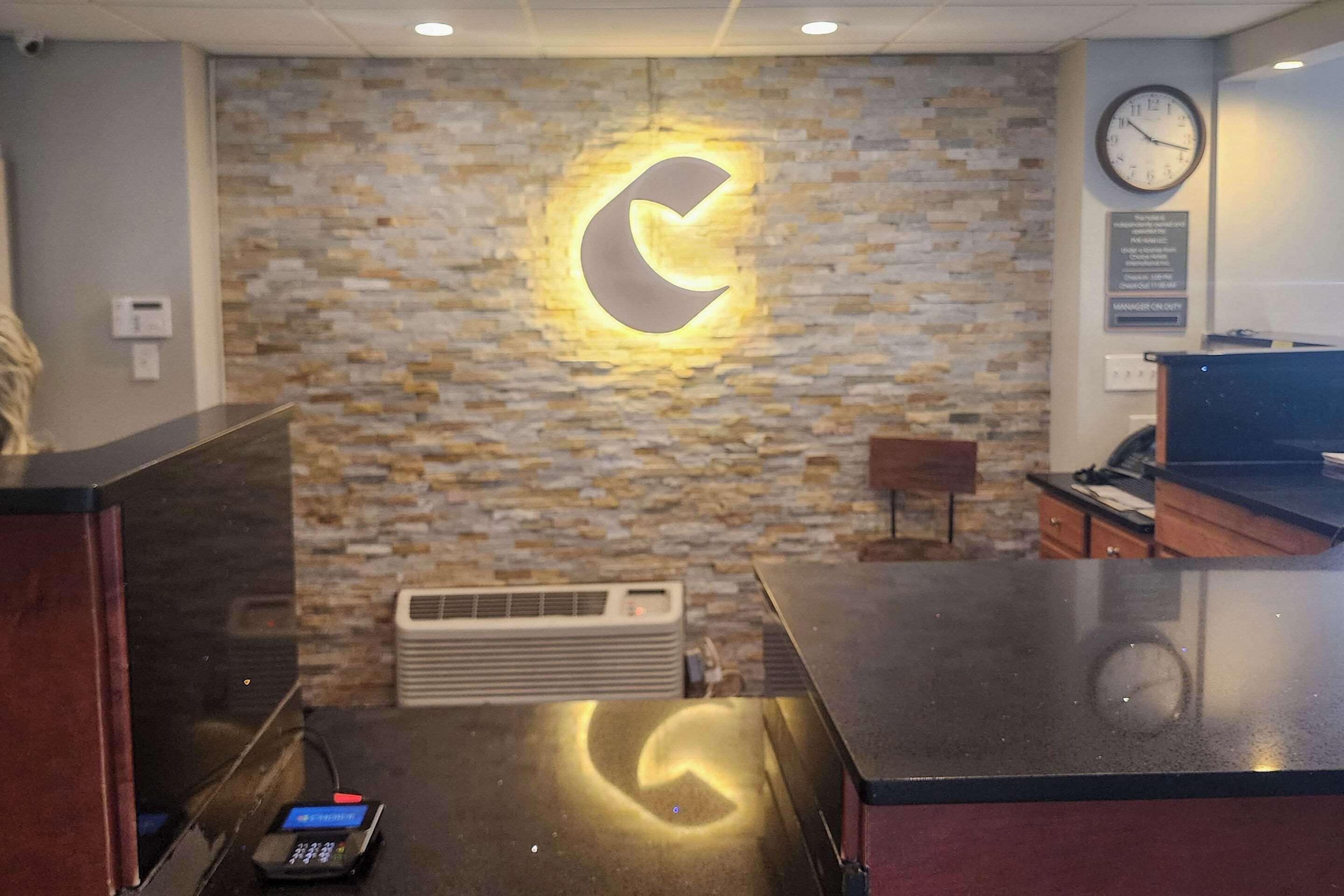 A reception area with a stone wall, a clock, and a digital display.