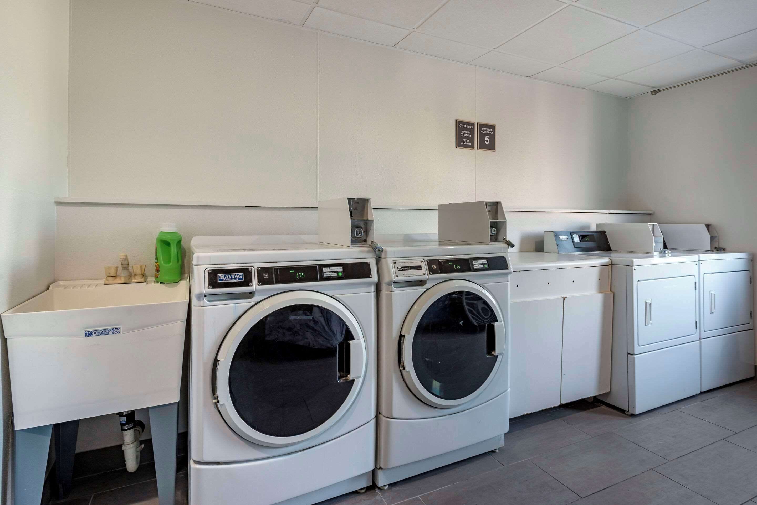 A laundry area with two front-loading washing machines, a sink, and a cabinet.