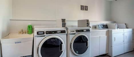 A laundry area with two front-loading washing machines, a sink, and a cabinet.