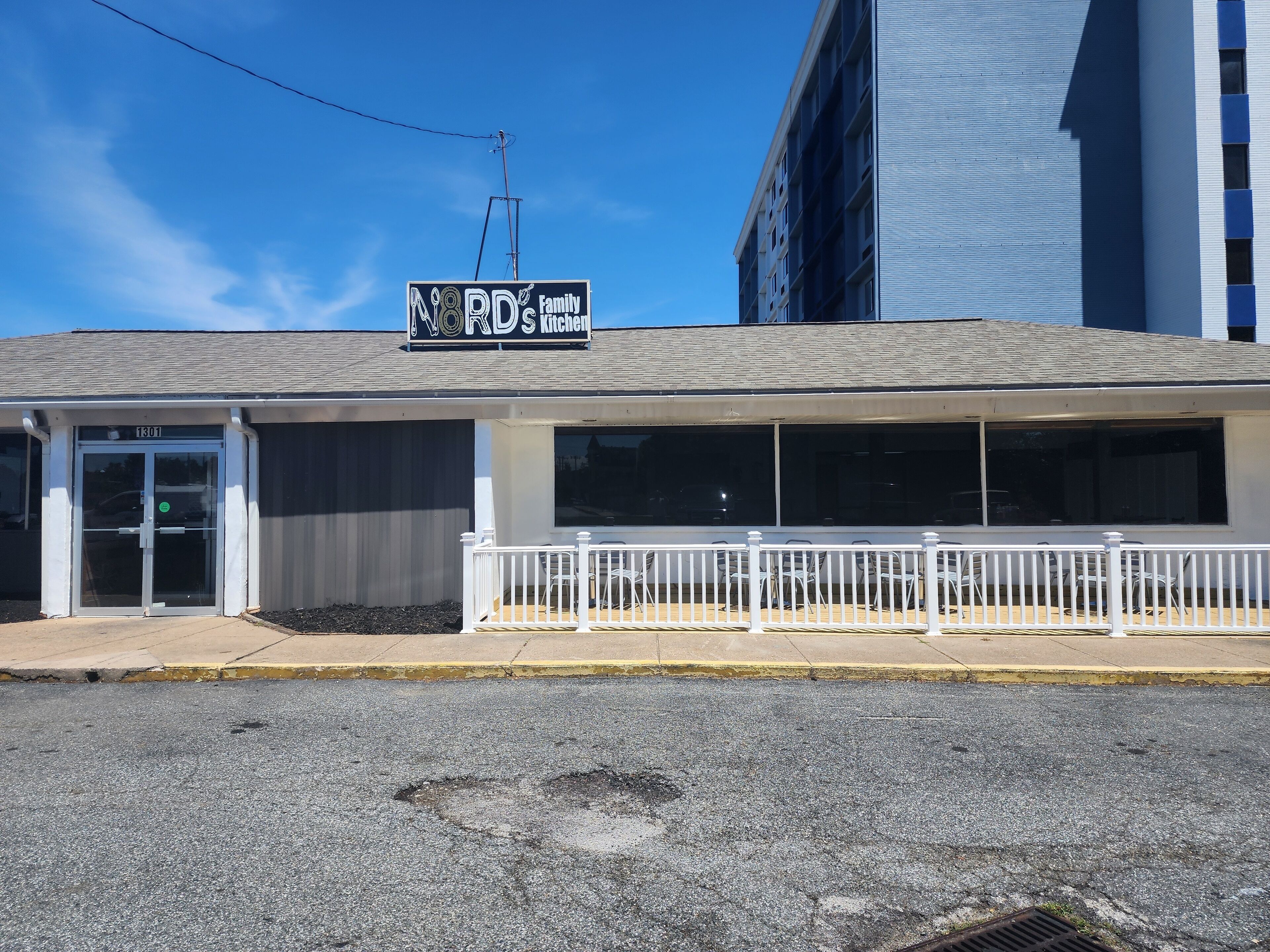 Un edificio con un letrero que dice "NOD's Kitchen" y una entrada con rejas.