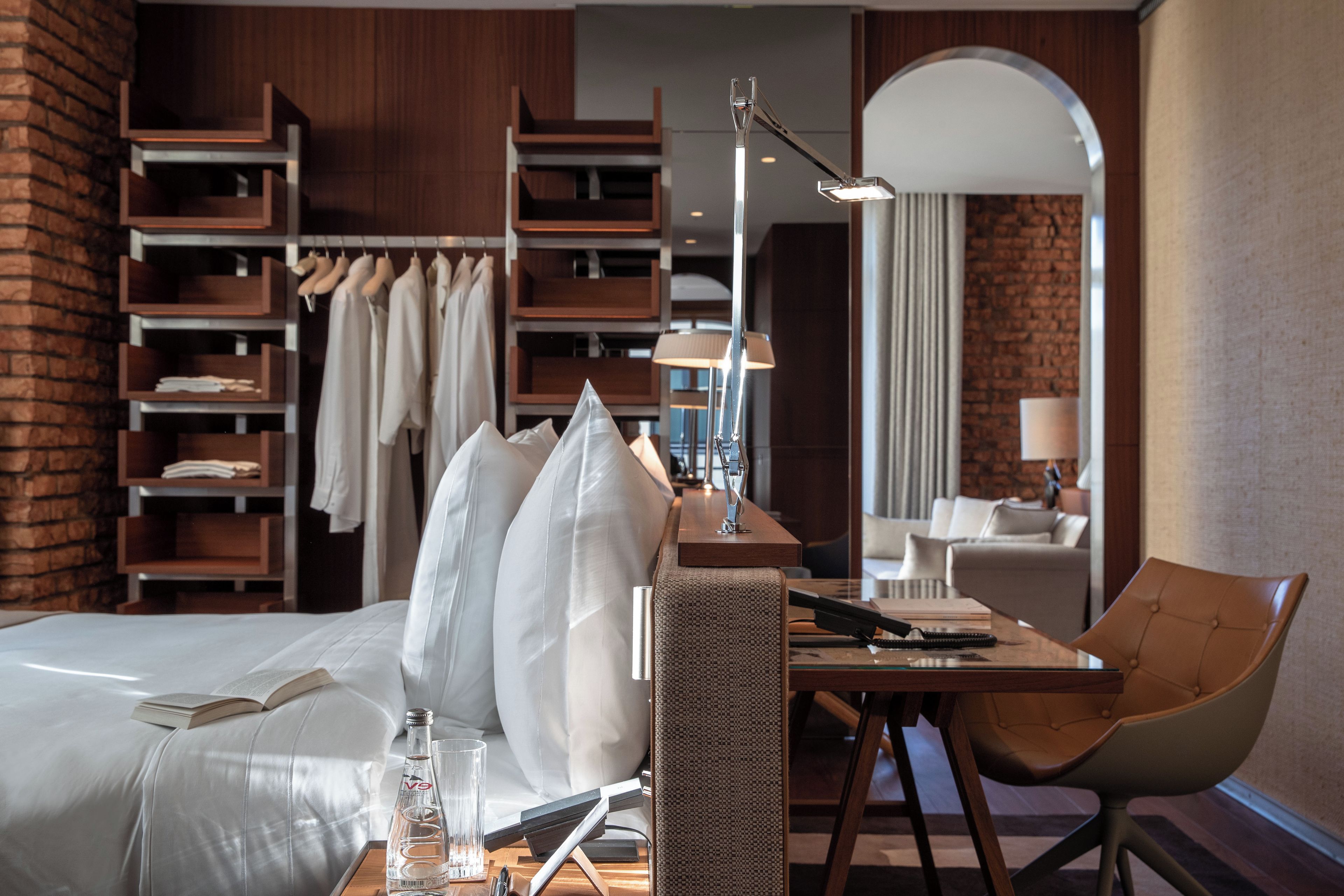 Una habitación de hotel con una cama, un escritorio, una silla, un armario y un espejo.
