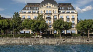 A large, historic building with a dome and multiple balconies, situated by a body of water.