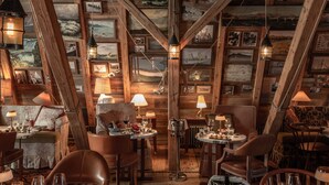 A cozy, rustic dining area with wooden beams, framed pictures, and warm lighting.