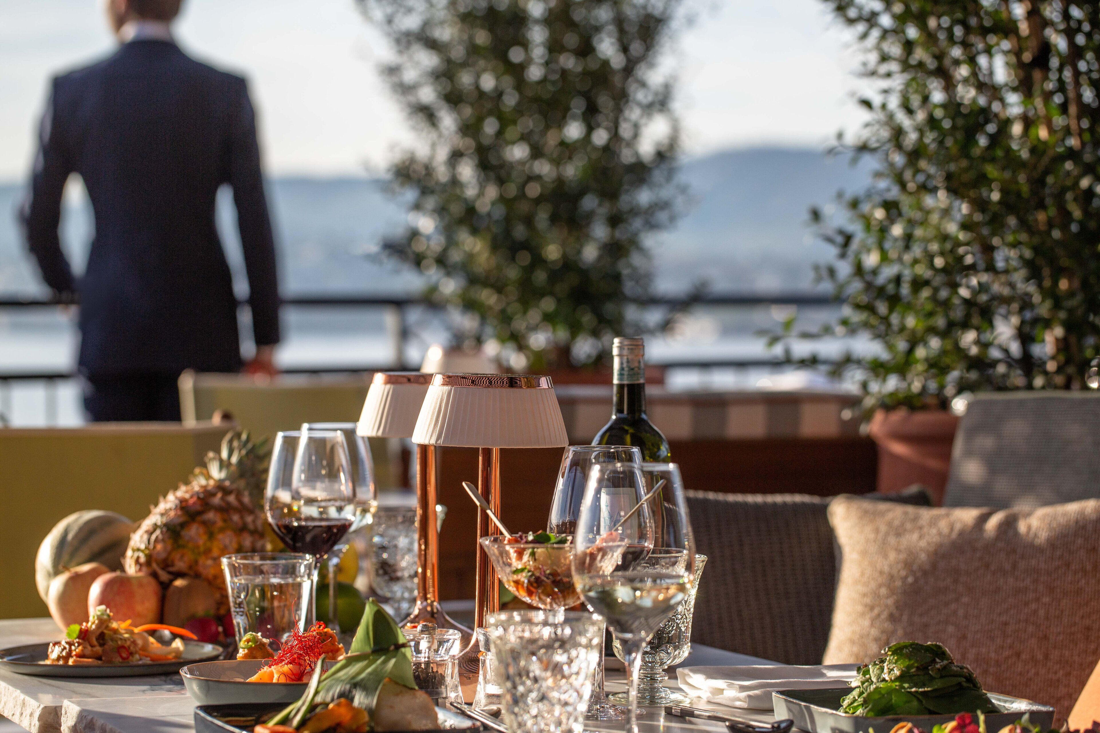 Une table à manger dressée avec différents plats, des verres et une bouteille, offrant une vue panoramique.