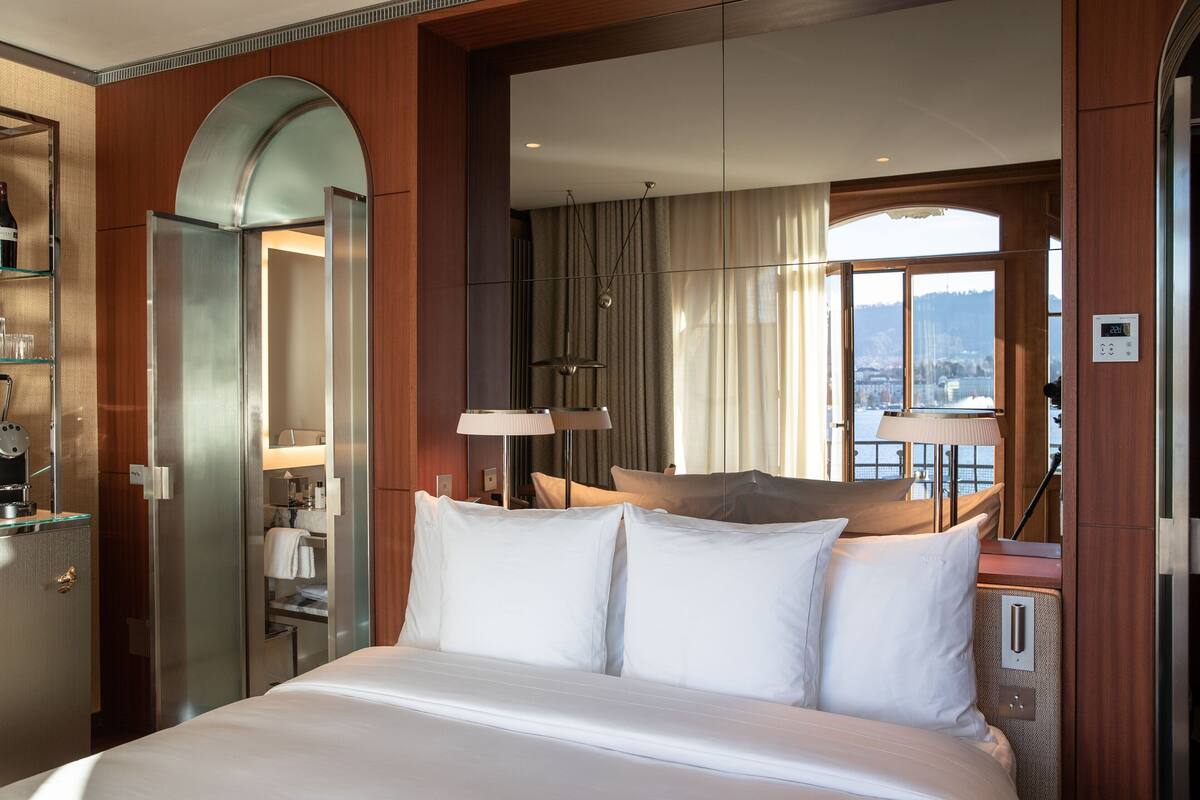 Een hotelkamer met een groot bed, een minibar, een badkamer en uitzicht op de stad door het raam.