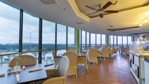 A spacious dining area with high ceilings and large windows offering a city view.