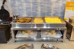 Un bufé con diversas opciones de comida, incluyendo pollo frito, macarrones con queso y otros platos.