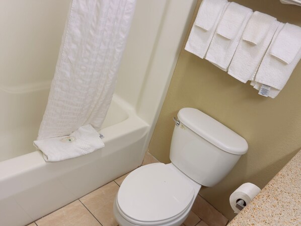 Un baño con bañera, inodoro y un perchero con varias toallas.