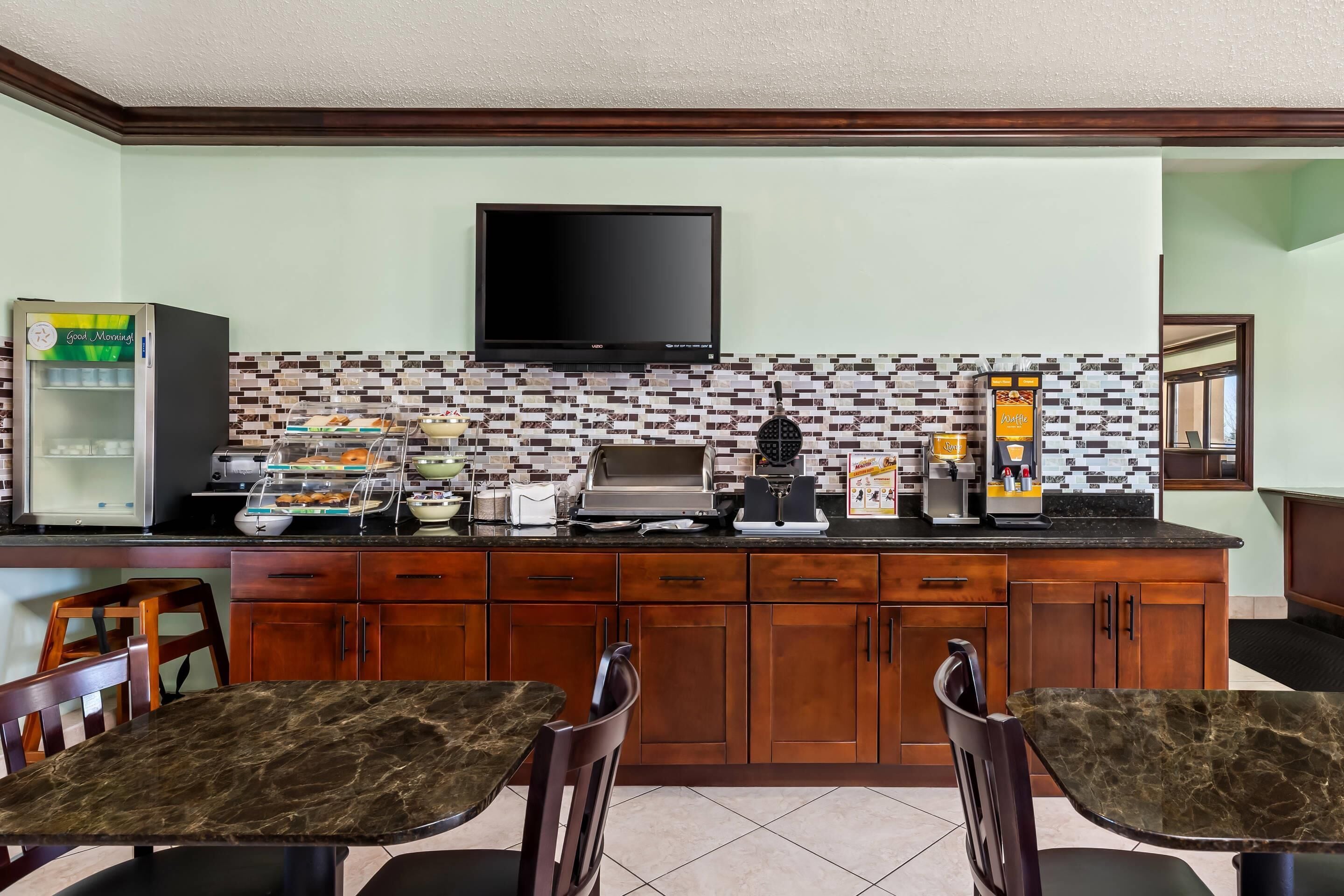 Una cocina equipada con televisión de pantalla plana, cafetera y refrigerador.