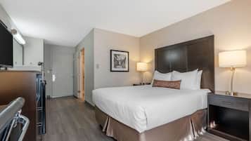 Une chambre d’hôtel dotée d’un grand lit, de lampes de chevet, d’un téléviseur à écran plat, d’un bureau avec une lampe et d’une porte donnant sur une salle de bain.