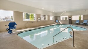 An indoor swimming pool with clear blue water, a lifeguard chair, and lounge chairs. - Best Western Inn Of Vancouver (Vancouver)