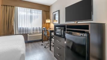 Habitación de hotel con cama, escritorio con computadora, televisor de pantalla plana, microondas y refrigerador.