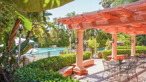 A pool area with a covered patio, outdoor seating, and lush greenery. - Uptown Oasis San Jose Airport & Silicon Valley (San Jose)