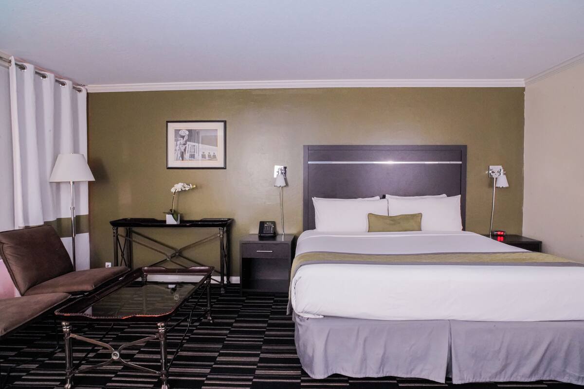 Ein Hotelzimmer mit einem großen Bett, einer Couch, einem kleinen Tisch und einem Nachttisch.
