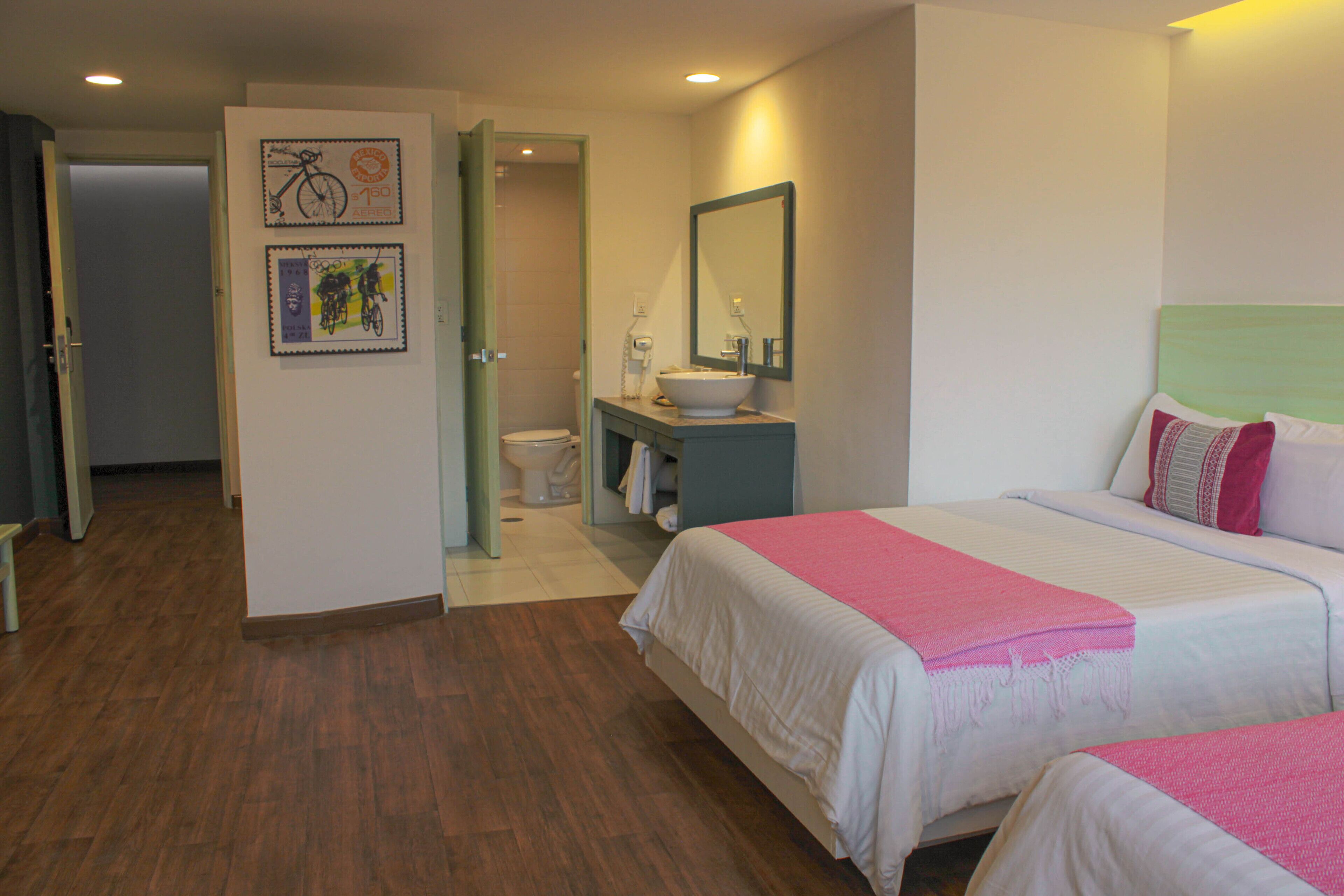 A hotel room with two beds, a bathroom, and a door leading to another room.