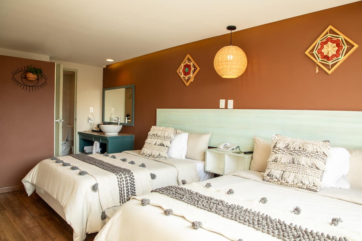 A hotel room with two beds, a bathroom, and a large mirror.