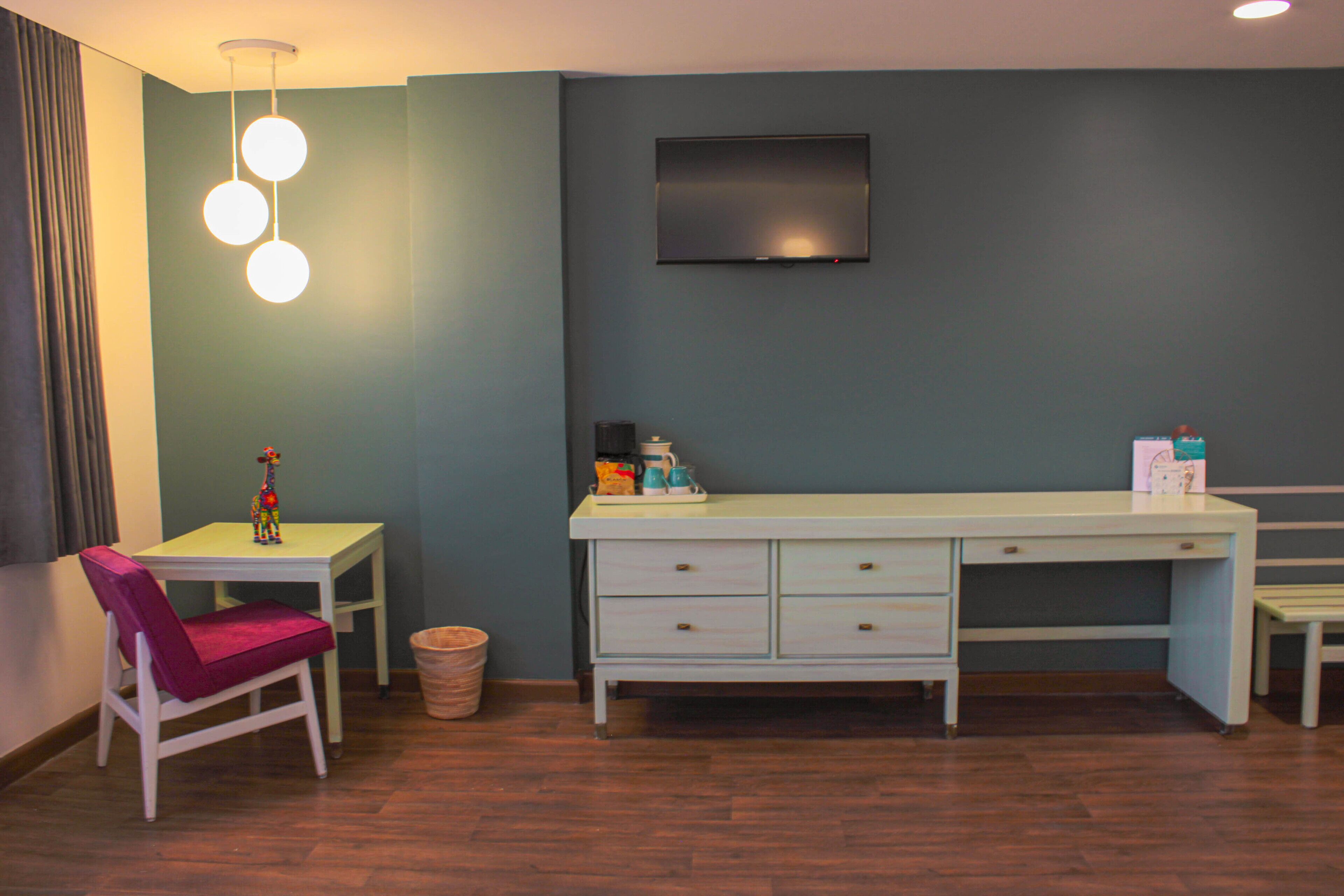 Um quarto com uma escrivaninha, cadeira e televisão na parede.