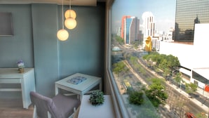 A modern room with a view of a cityscape, a small table with a plant, and a hanging light fixture. - Hotel Fontan Reforma Centro Histórico (Mexico City)