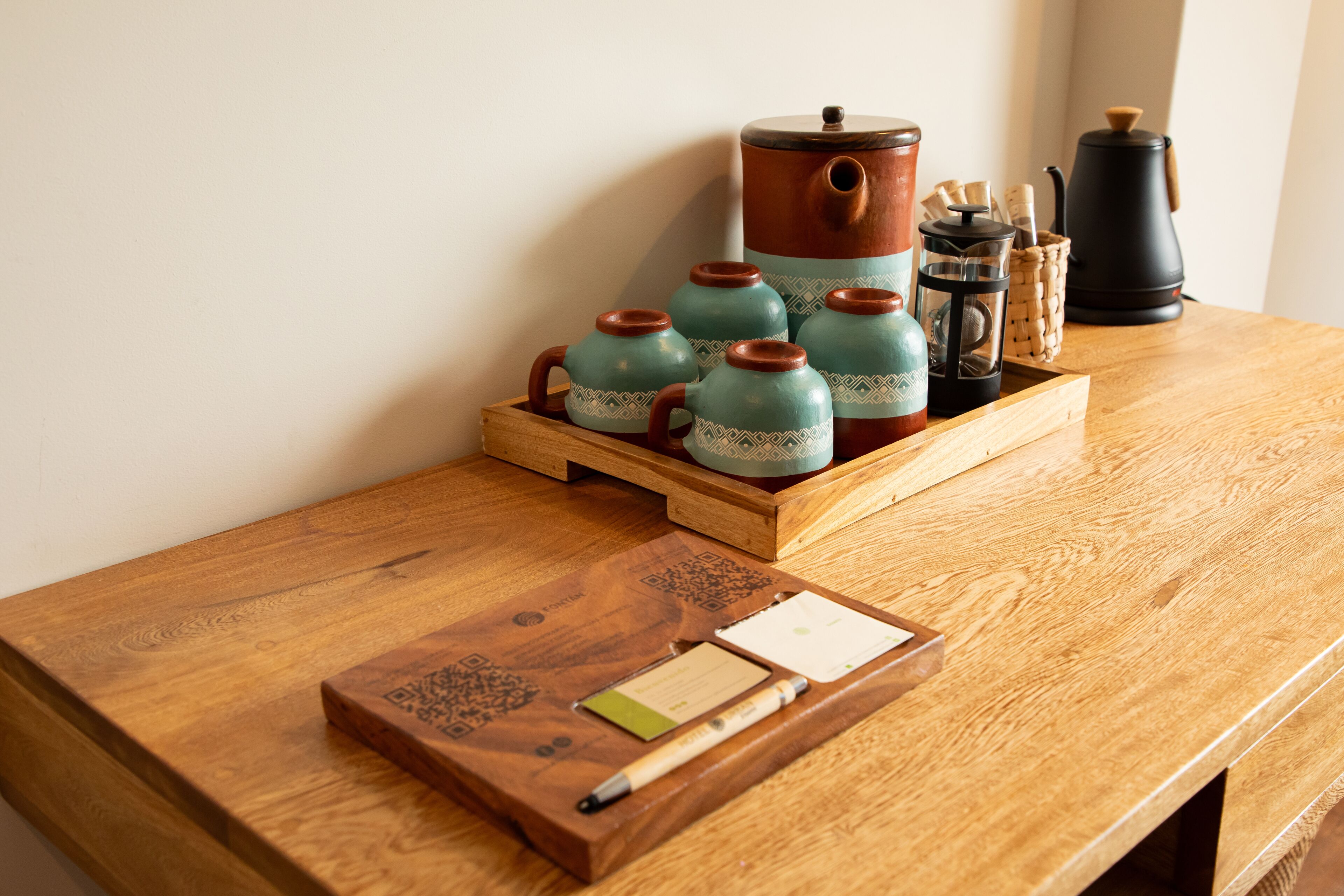 A wooden table with a tray holding ceramic teapots, a coffee pot, and a French press.