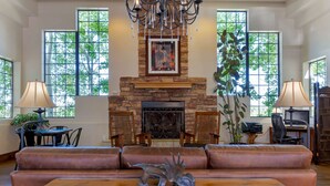 A spacious living room with a stone fireplace, leather sofa, and a glass coffee table. - Best Western Paint Pony Lodge (Show Low)