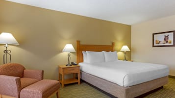 A hotel room with a bed, two bedside tables with lamps, a chair, and a framed picture on the wall.
