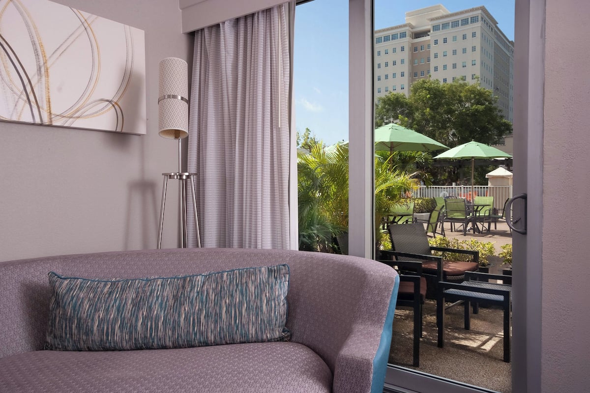 Habitación de hotel moderna con un amplio ventanal, vistas al patio exterior y un diseño interior contemporáneo.