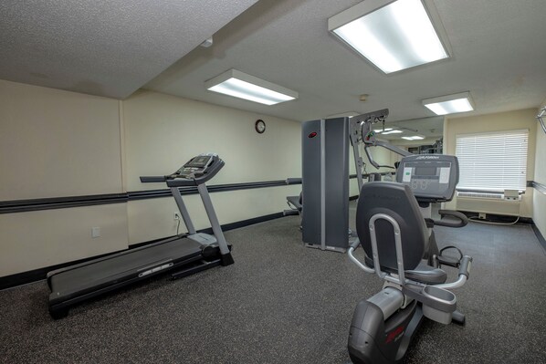 A gym with a treadmill, elliptical, and weight machine. - Red Roof Inn Charlotte - University (Charlotte)