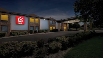A Red Roof Inn with a brick facade, multiple windows, and a covered parking area.
