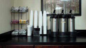 Un coin café avec des gobelets jetables, des sachets de thé Lipton et des machines à café Bunn, le tout installé sur un comptoir.