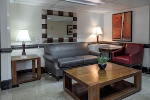 Relax in comfort with a sofa, armchair, and potted plant, surrounded by artwork and ample lighting.