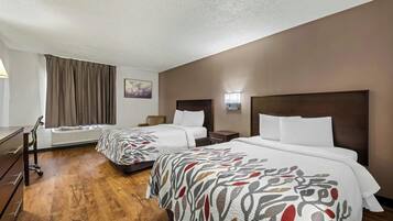 A hotel room with two beds, a desk, and a chair.