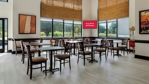 A spacious room with multiple tables and chairs, large windows with blinds, and a sign indicating free Wi-Fi availability. - Red Roof Inn Charlotte - University (Charlotte)