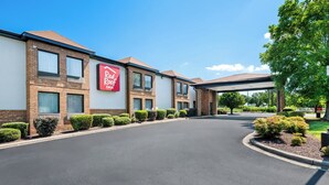 A Red Roof Inn with a covered driveway and well-maintained landscaping. - Red Roof Inn Charlotte - University (Charlotte)