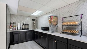 A modern kitchen with black cabinets, a herringbone tile backsplash, and a coffee machine. - Red Roof Inn Charlotte - University (Charlotte)