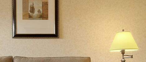 A hotel room with a sofa, a table, a lamp, and a framed picture on the wall.